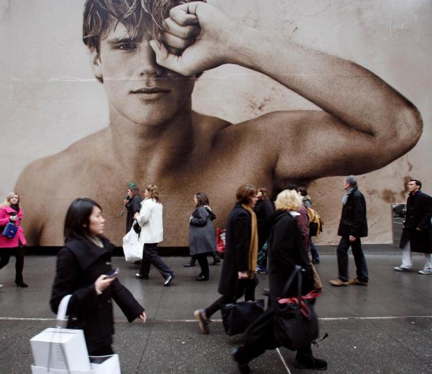 shoppers walk past a billboard for an Abercrombie & Fitch store in New York